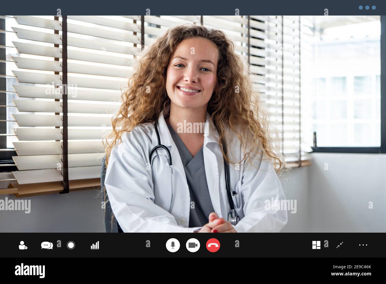 Smiling cheerful Caucasian woman doctor looking at the camera while having online meeting with patient,  home medical consulation video call service c Stock Photo
