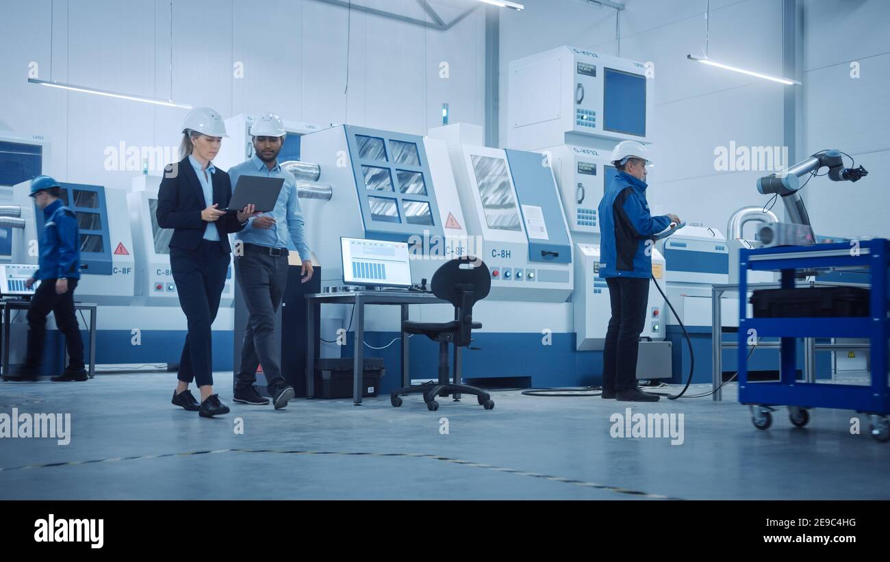 Modern Factory with Professional Workers, Engineers, Managers Working on Production Line, Workshop Management, Optimization. Industrial Facility Stock Photo