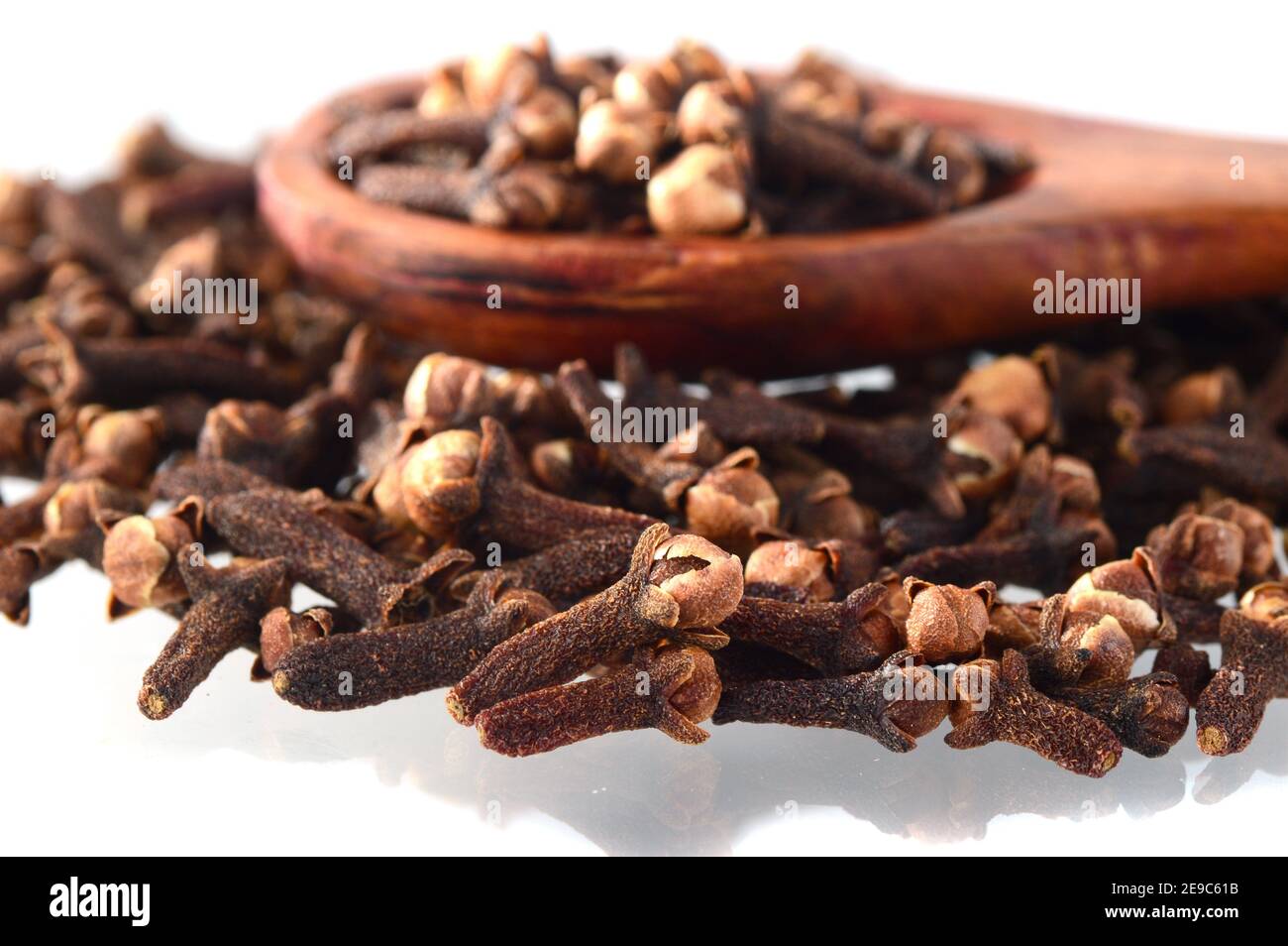 Cloves (spice) and wooden spoon close-up food background. Isolated on white background. Stock Photo