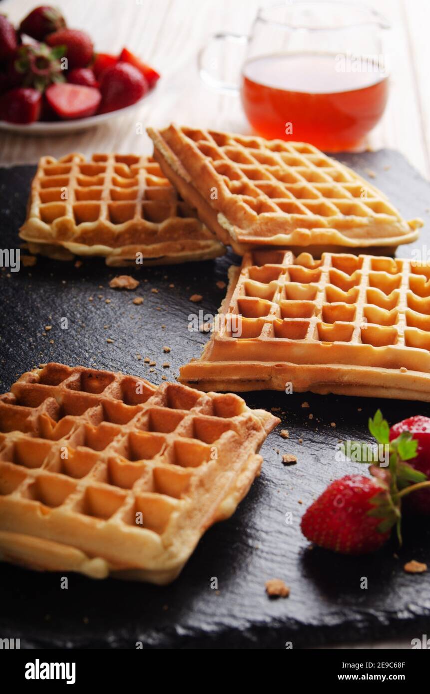 Homemade Belgian waffles on slate tray with maple syrup and