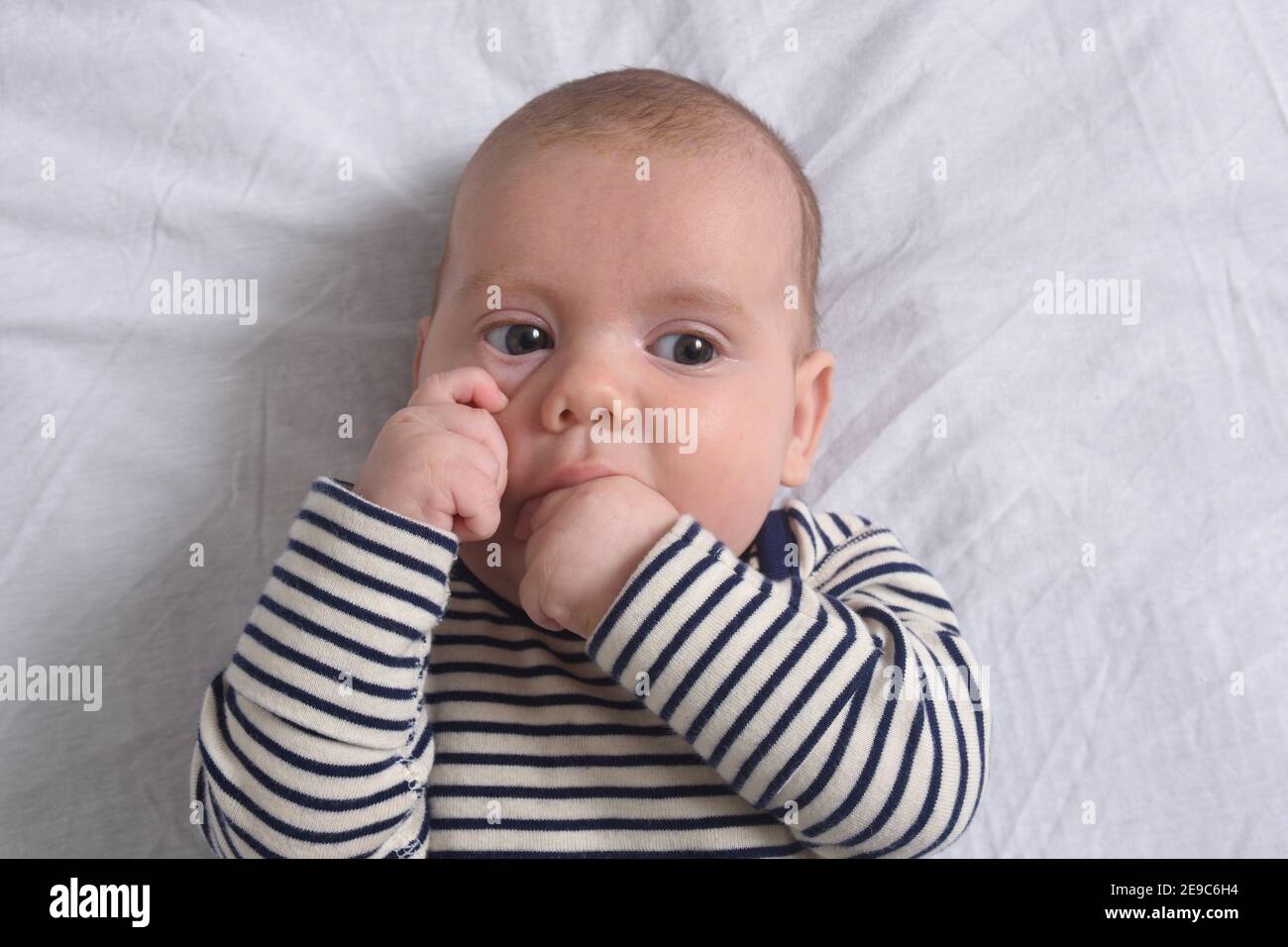 the baby who puts his hand in his mouth to suck his finger Stock Photo