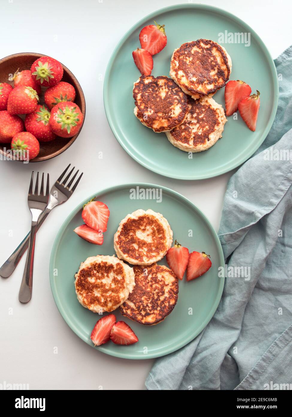 Sweet cheese pancakes on plate served strawberries. Cottage cheese pancakes, syrniki, ricotta fritters, curd fritters. Top view or flat lay. Vertical. Stock Photo