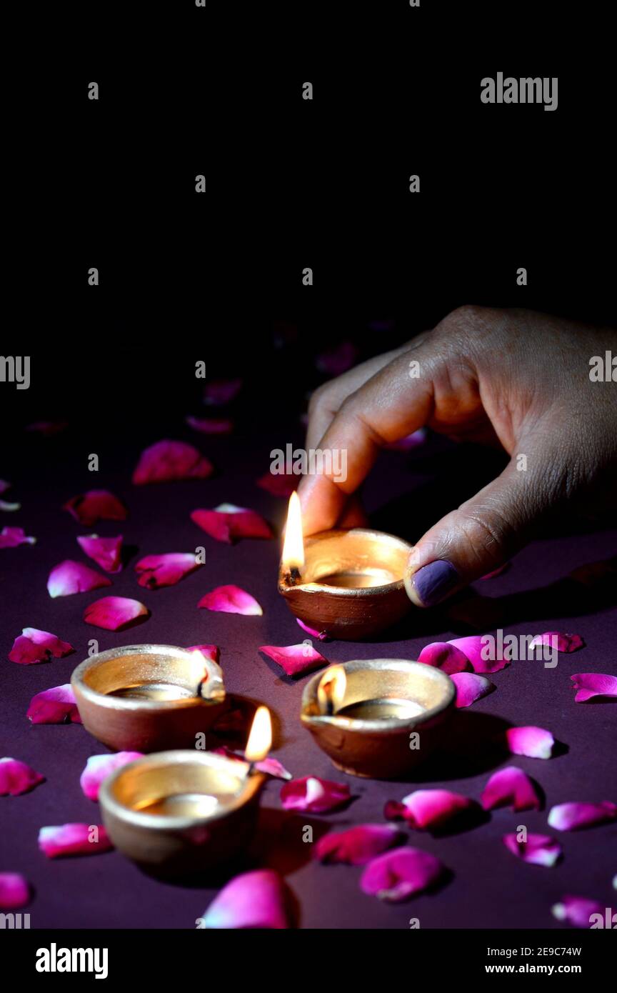 Hand holding and arranging lantern (Diya) during Diwali Festival of Lights. Stock Photo