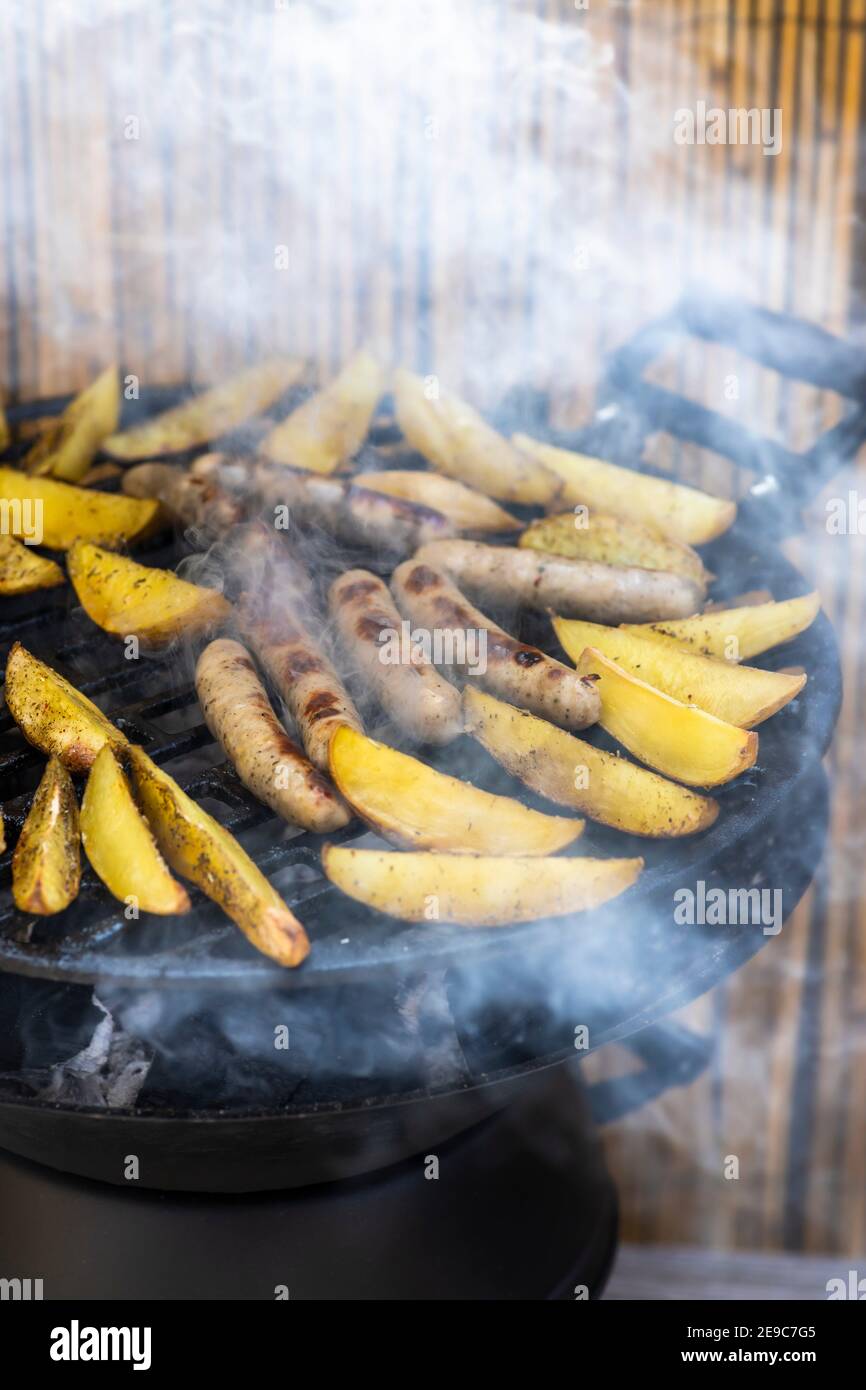 charcoal garden grill with potatoes and sausages Stock Photo Alamy