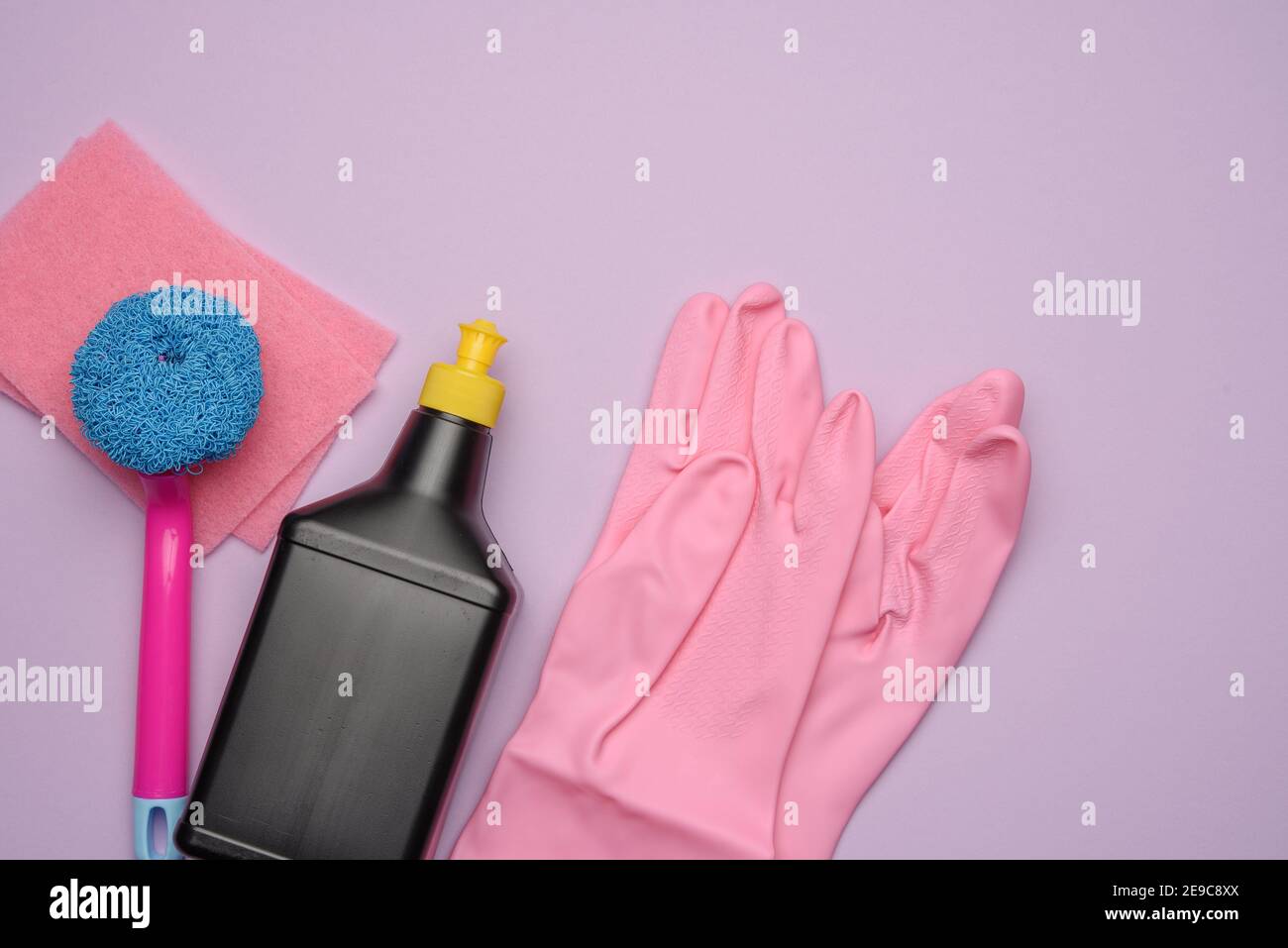 black plastic bottle and pink rubber gloves for cleaning, brushes on a