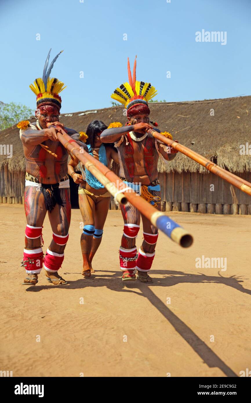Two native indios with a young girl in festive clothing and feathres in  their hair playing their long pipe, Mato Grosso, Brazil, South America  Stock Photo - Alamy