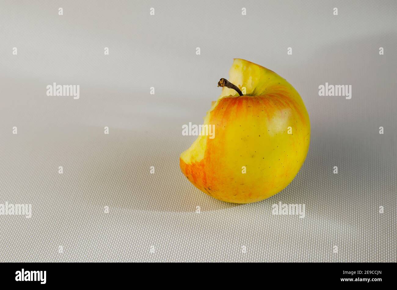 A half-eaten apple on a white background. A bitten ripe apple on a ...