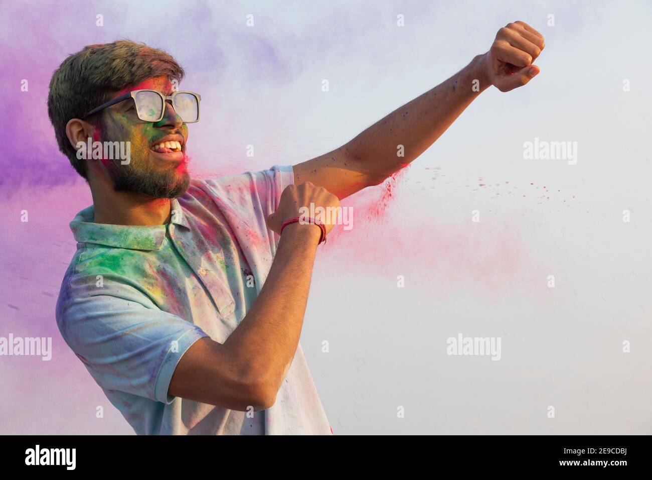 A YOUNG MAN HAPPILY DANCING DURING HOLI CELEBRATIONS Stock Photo