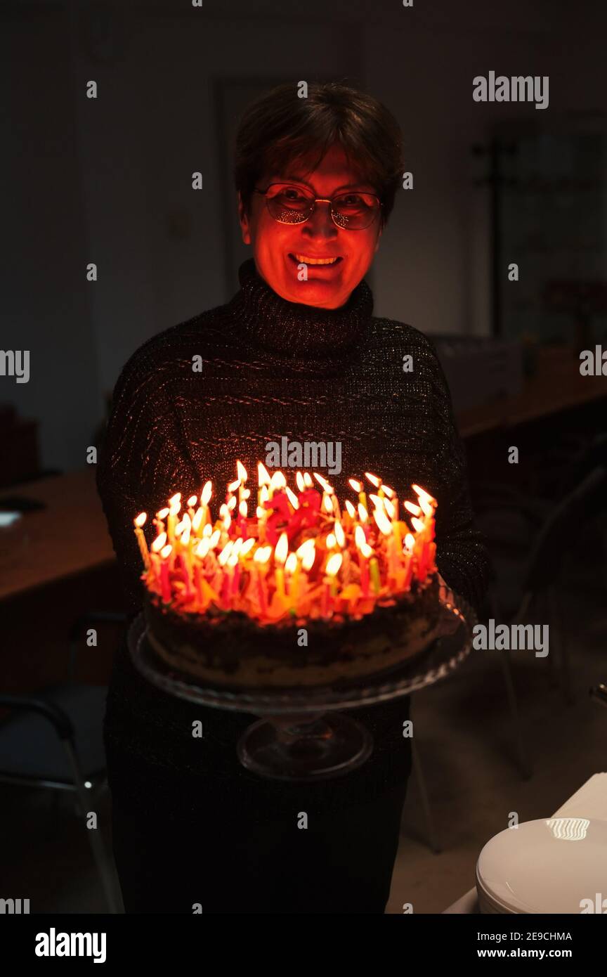 Portrait of senior woman holding birthday cake with candles Stock Photo