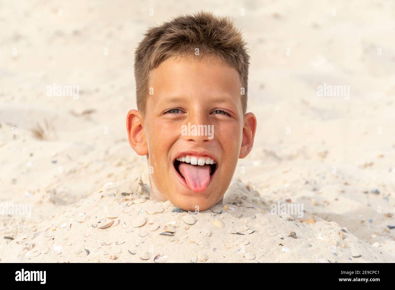 Head of a boy buried in the sand. Summer fun Stock Photo Alamy