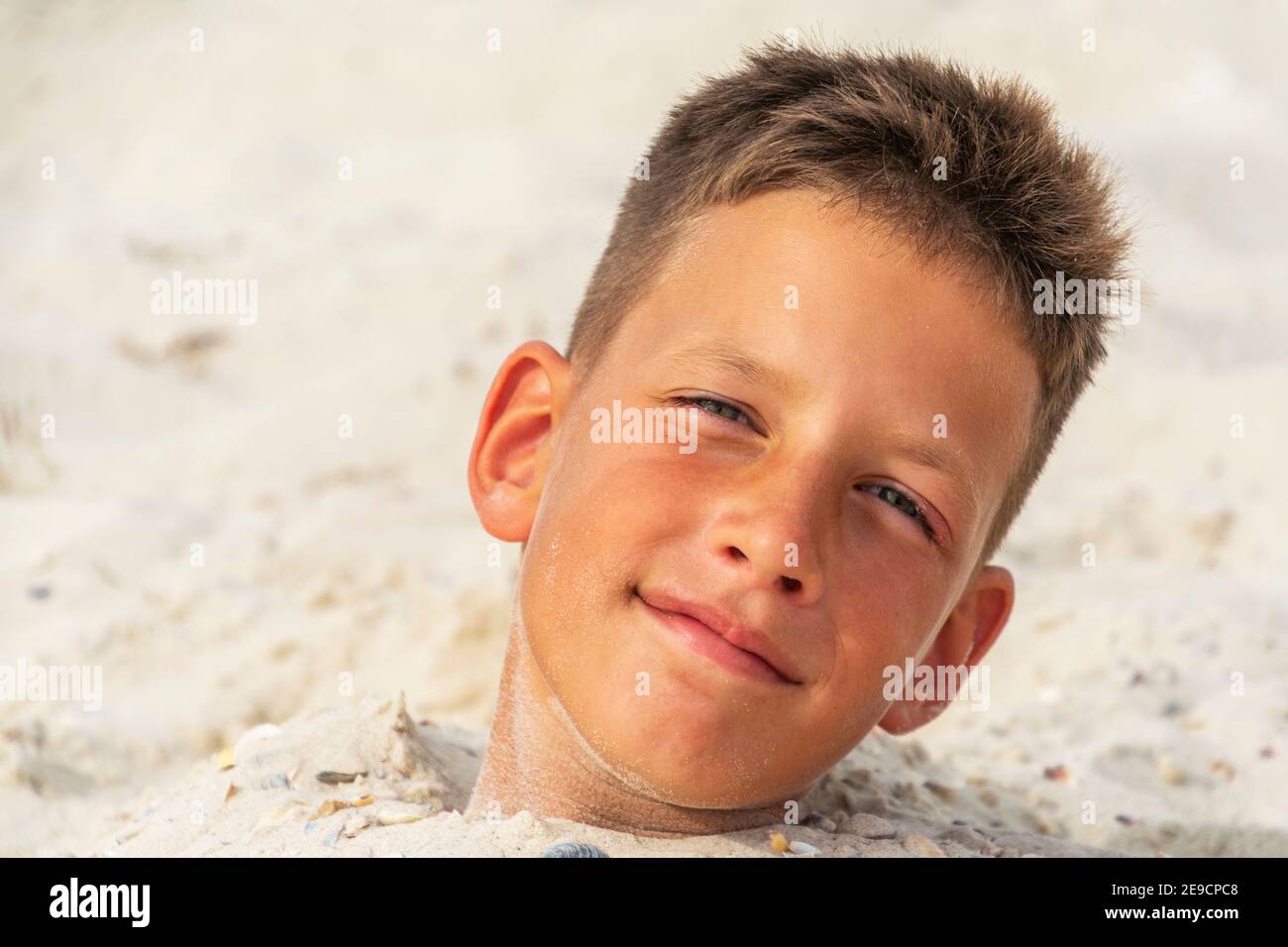 Head of a boy buried in the sand. Summer fun Stock Photo Alamy