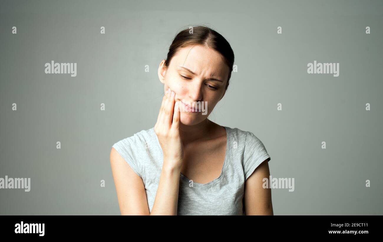 A woman with a pain in her teeth clutches her face Dentist medicine