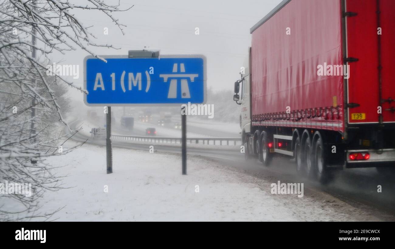 lorry passing A1m motorway sign in winter snow Leeds Yorkshire United Kingdom Stock Photo