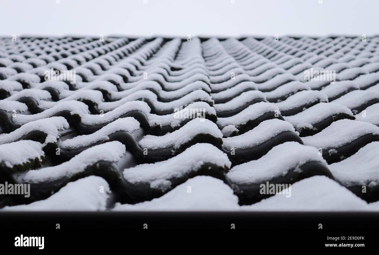Closeup of snow on roof tiles of a European house during winter Stock Photo