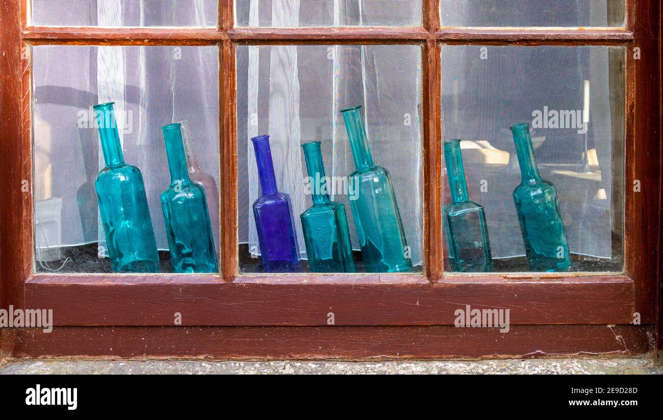 Seven Blue glass bottles on display on a window sill Stock Photo