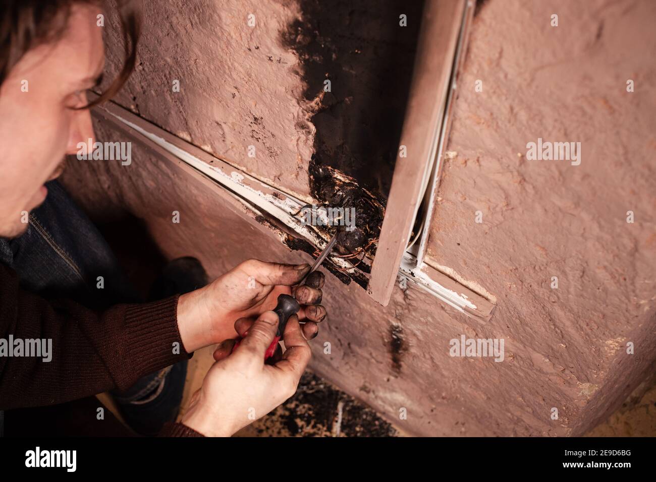 A man fixes a burnt socket. Short circuit, burnt wires. traces of smoke