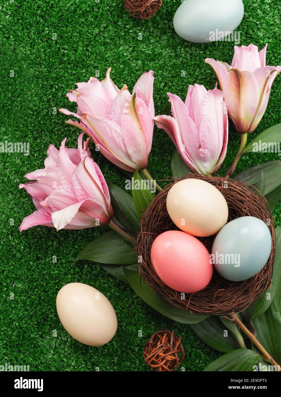 Colorful Easter eggs in the nest with pink lily flower on on a lawn ...