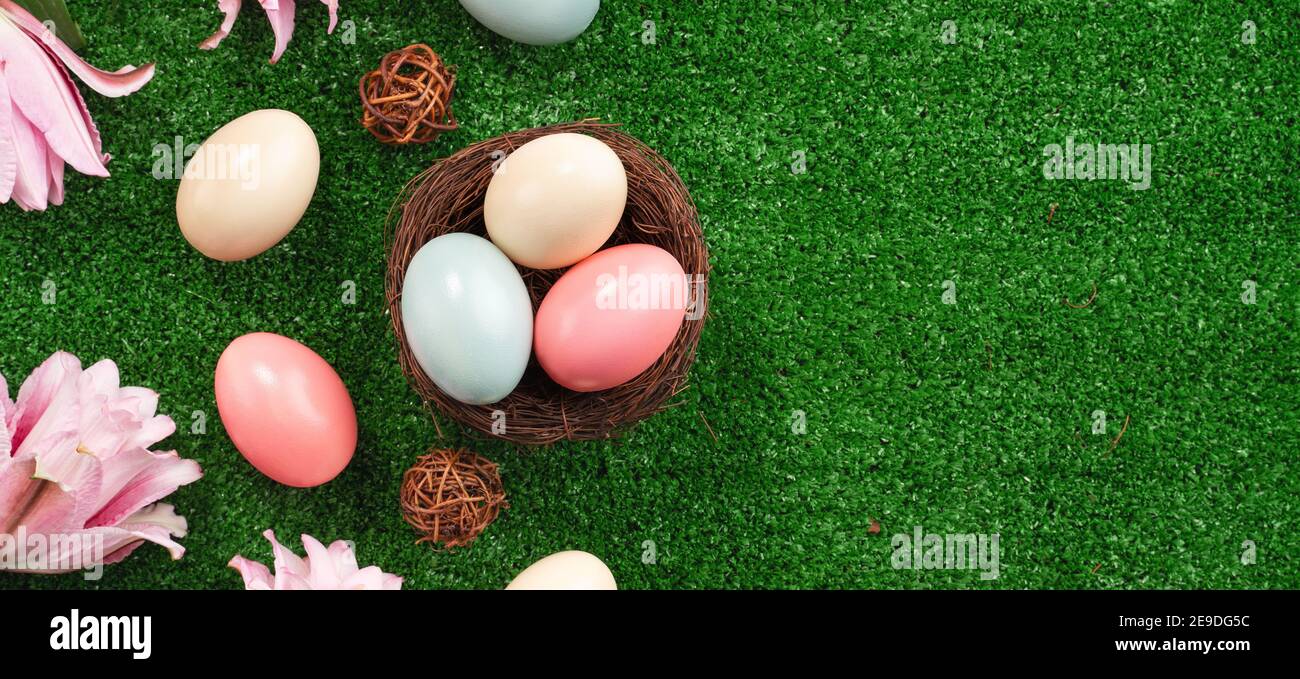 Colorful Easter eggs in the nest with pink lily flower on on a lawn ...