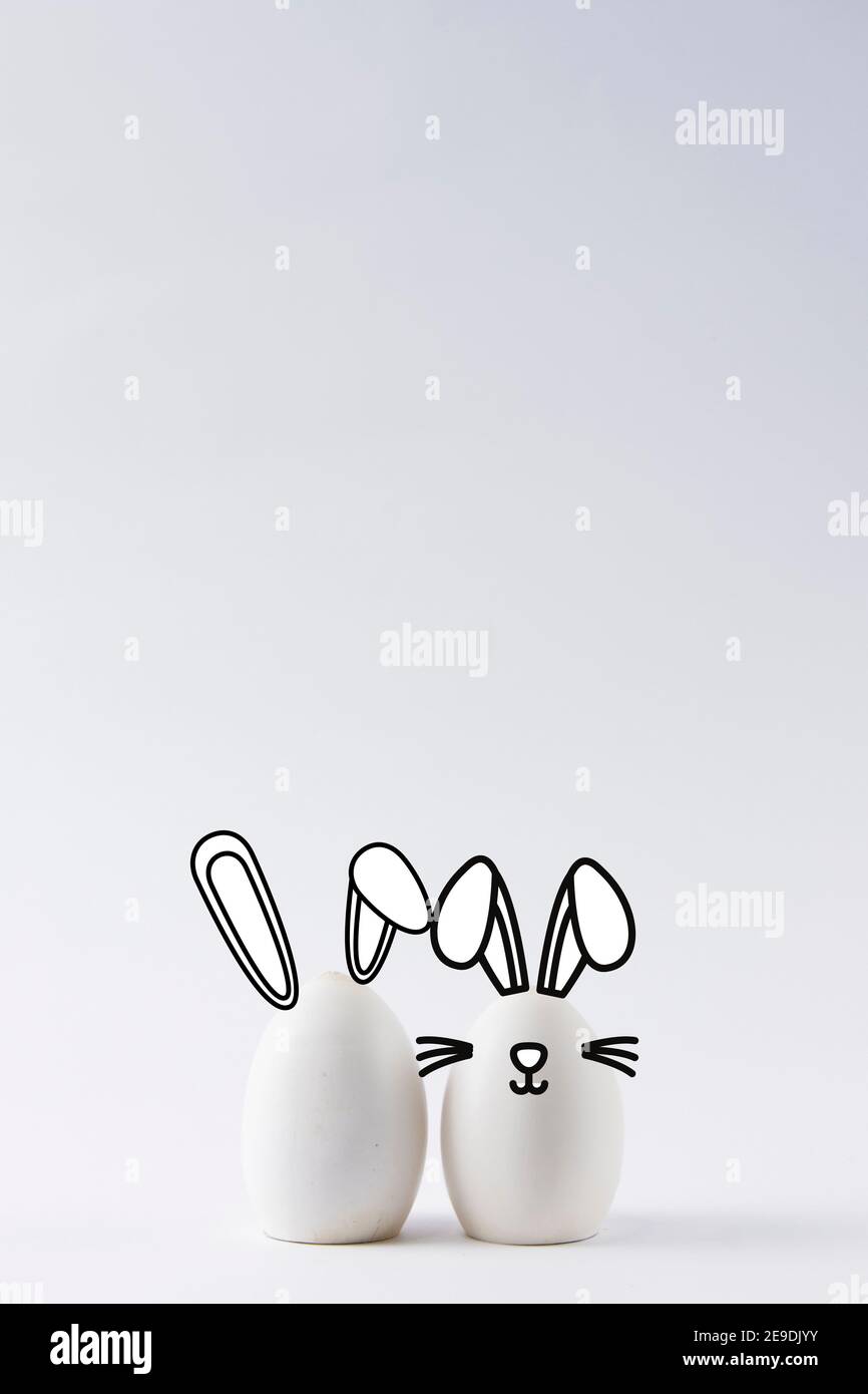 Close-up of some white eggs on white background with bunny ears. Easter bunny concept with bunny ears Stock Photo