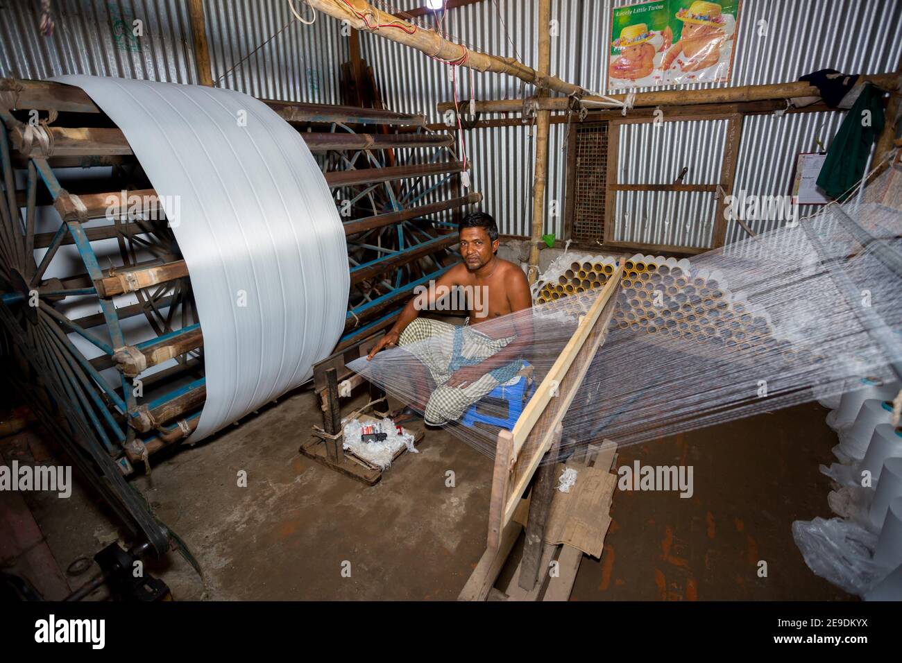 A factory worker makes white yarn spools for making clothes at Narsingdi, Bangladesh. Stock Photo