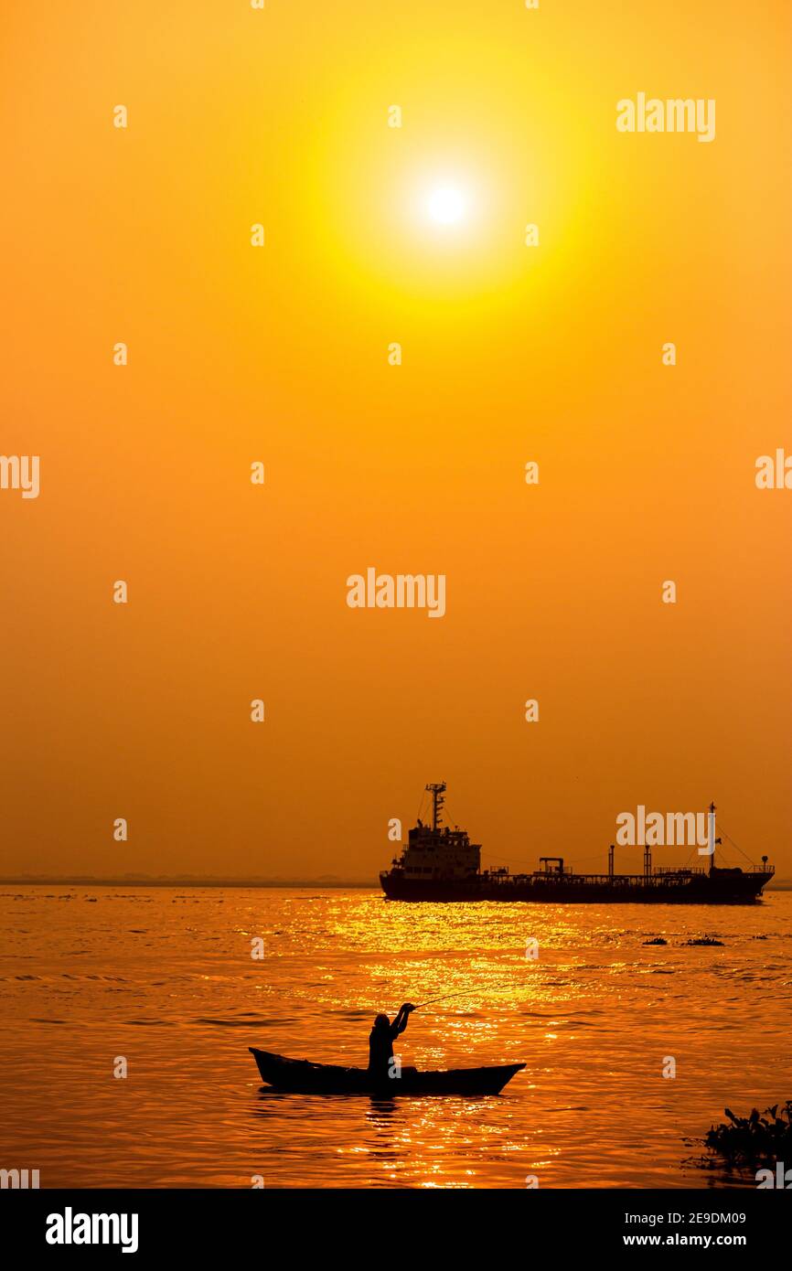 Evening golden sunset time, a fisherman fishing on the seaside on a boat. Stock Photo