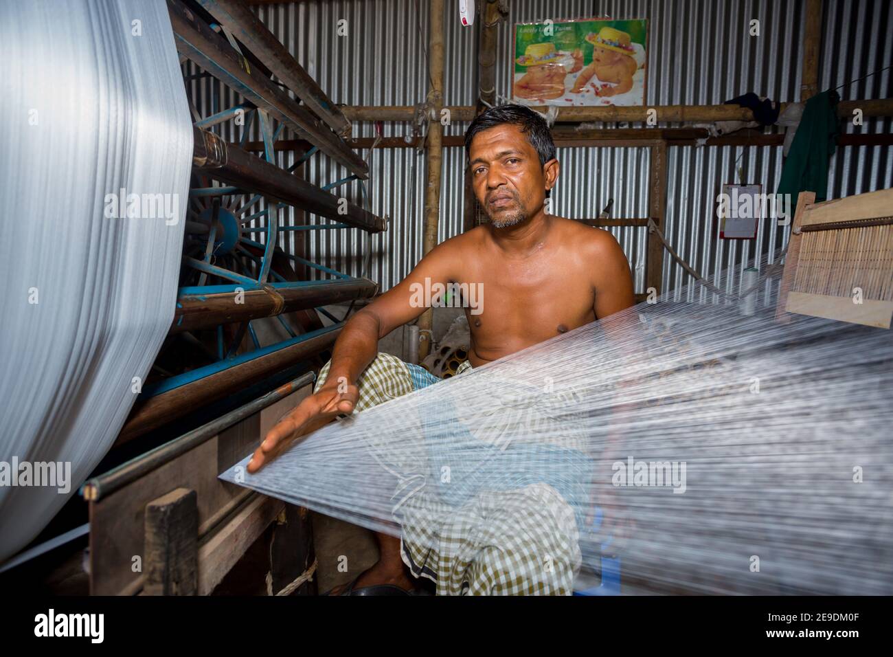 A factory worker makes white yarn spools for making clothes at Narsingdi, Bangladesh. Stock Photo
