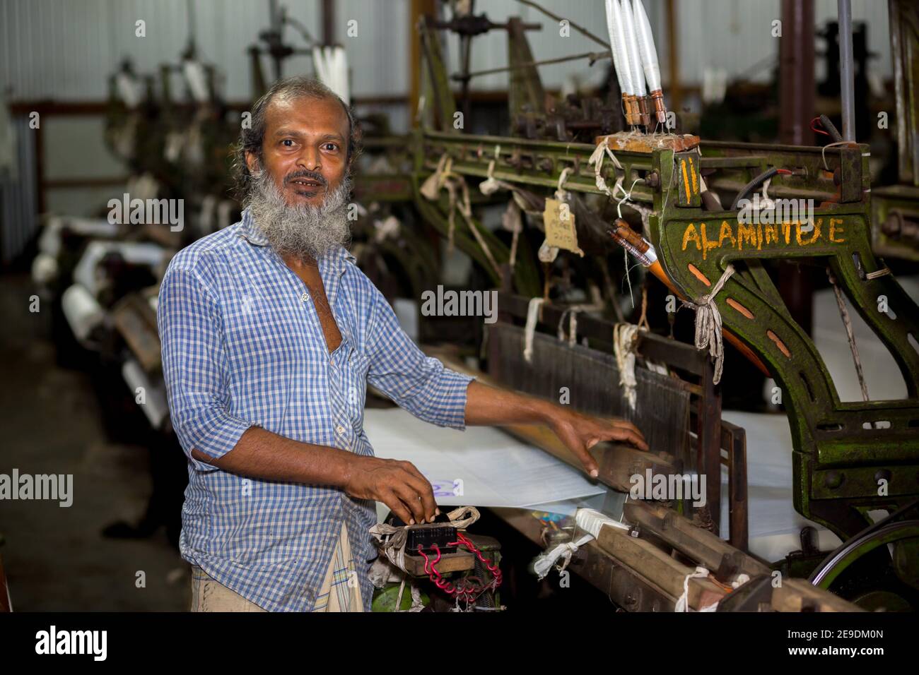 A yarn factory worker has made white cotton cloth in the machine at Narsingdi, Bangladesh. Stock Photo