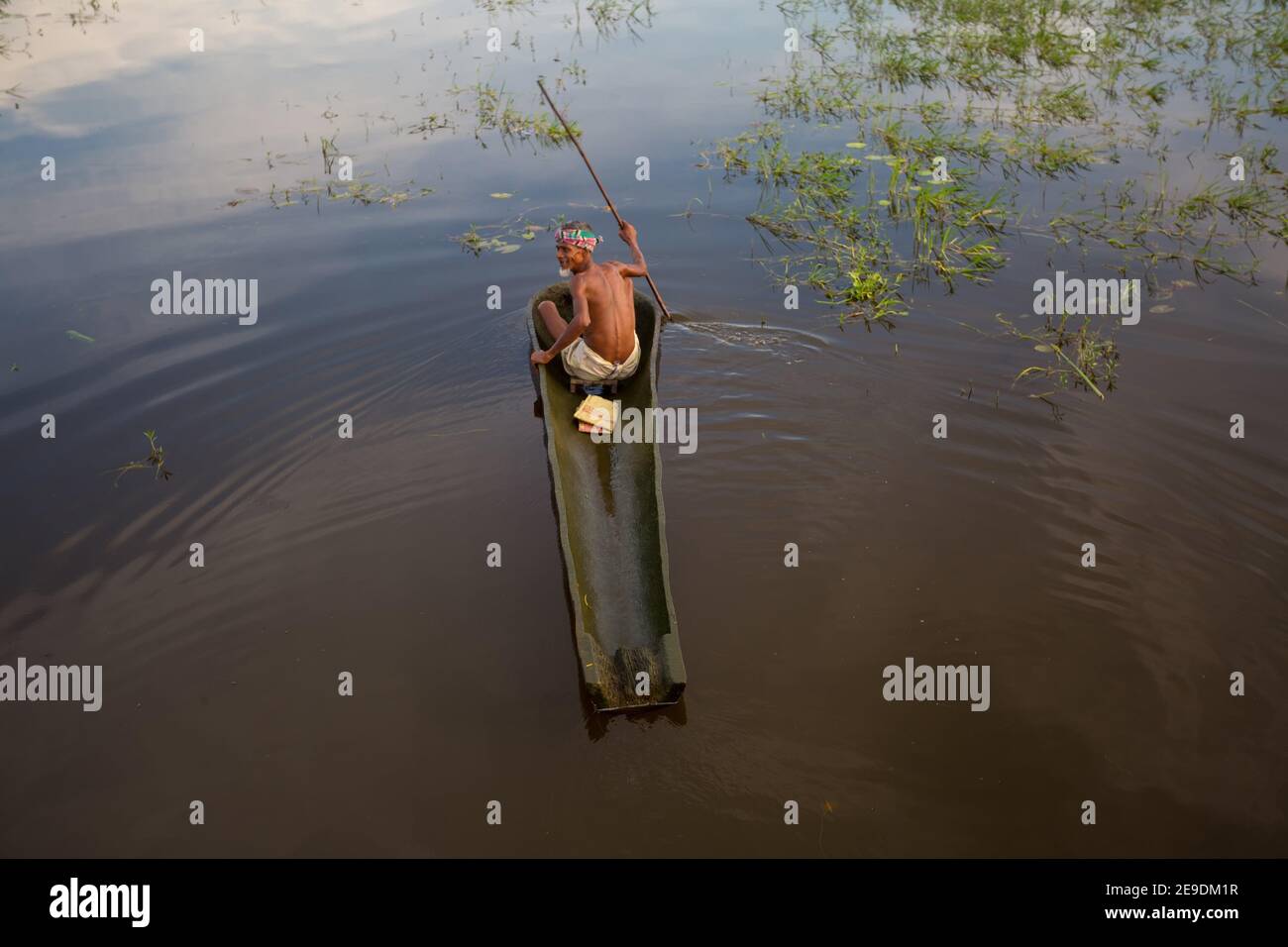 An old man is driving a boat made from the bark of his palm tree at Narsingdi, Bangladesh. Stock Photo