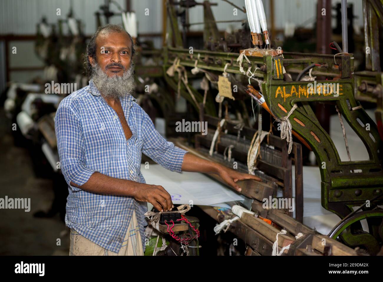 A yarn factory worker has made white cotton cloth in the machine at Narsingdi, Bangladesh. Stock Photo