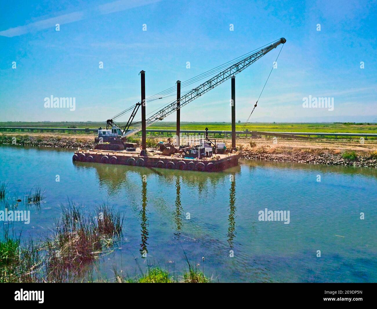 Construction crane on a barge in a canal near Stockton, California. Stock Photo