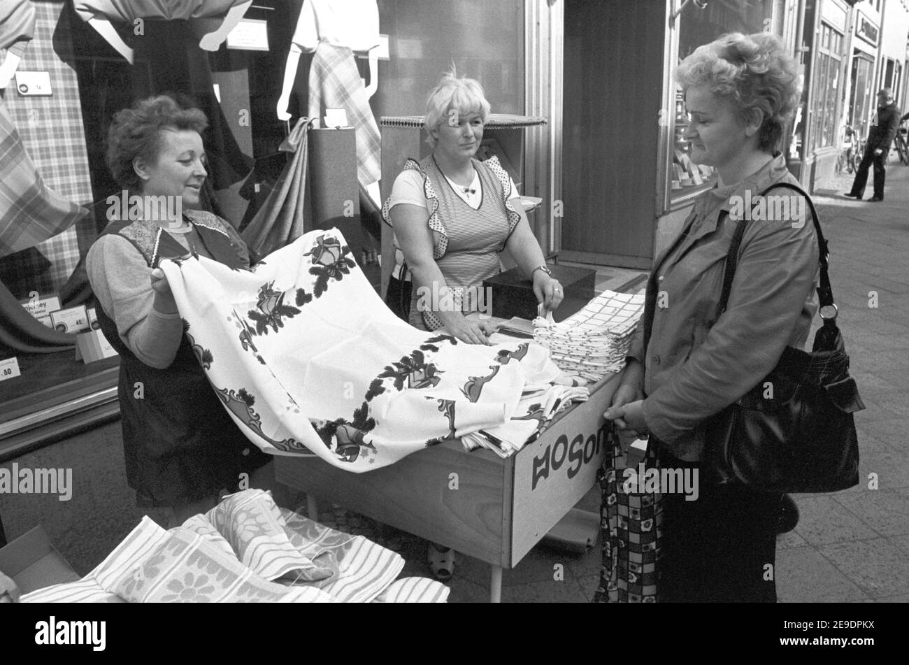 15 October 1984, Saxony, Eilenburg: HO Textilwaren saleswomen sell tablecloths and wiping cloths in front of their shop in autumn 1984 in Eilenburg. The exact date of the photo is not known. Photo: Volkmar Heinz/dpa-Zentralbild/ZB Stock Photo