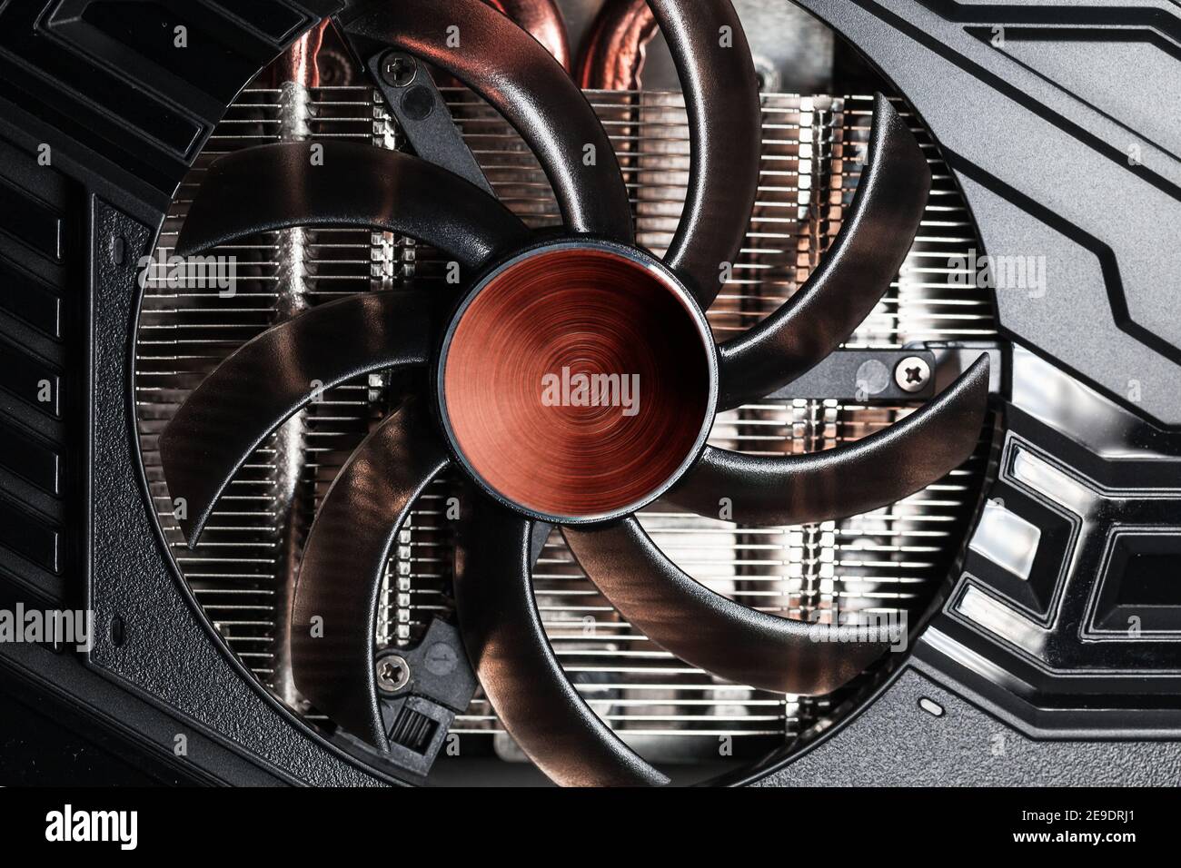 New shiny black GPU cooler with red center, close-up photo. This fan is mounted on a video card to cool the GPU and surrounding components Stock Photo