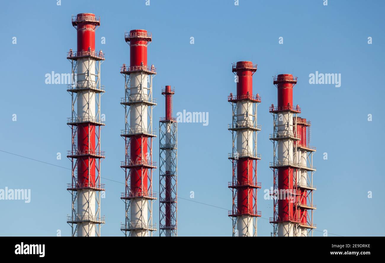 Red white metal chimneys under clear blue sky. Power plant equipment Stock Photo