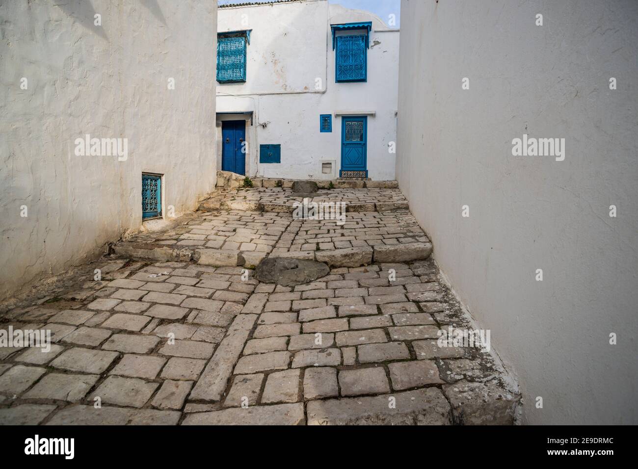 Traditional dwellings along a cobbled hillside street. Sidi Bou Said, the blue and white tourist village overlooking the Mediterranean Sea. Tunisia, Stock Photo