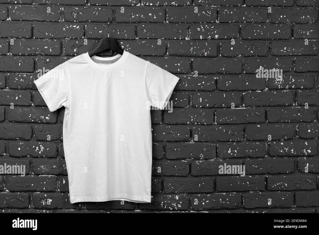 White t-shirt hanging on hanger against brick wall Stock Photo - Alamy