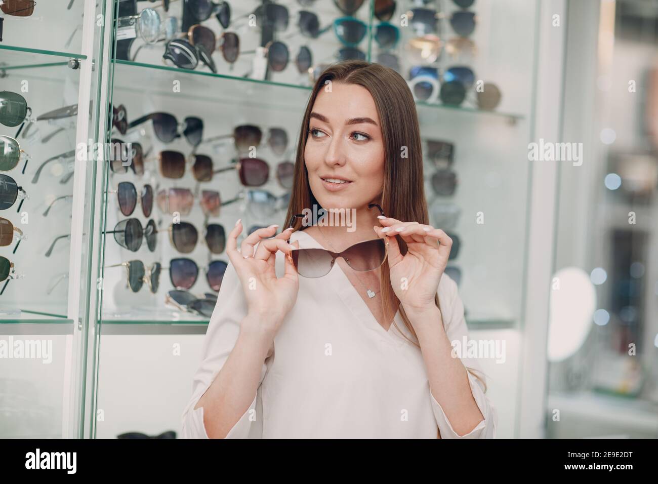 Close up of young woman smiling picking and choosing glasses at the optician corner at