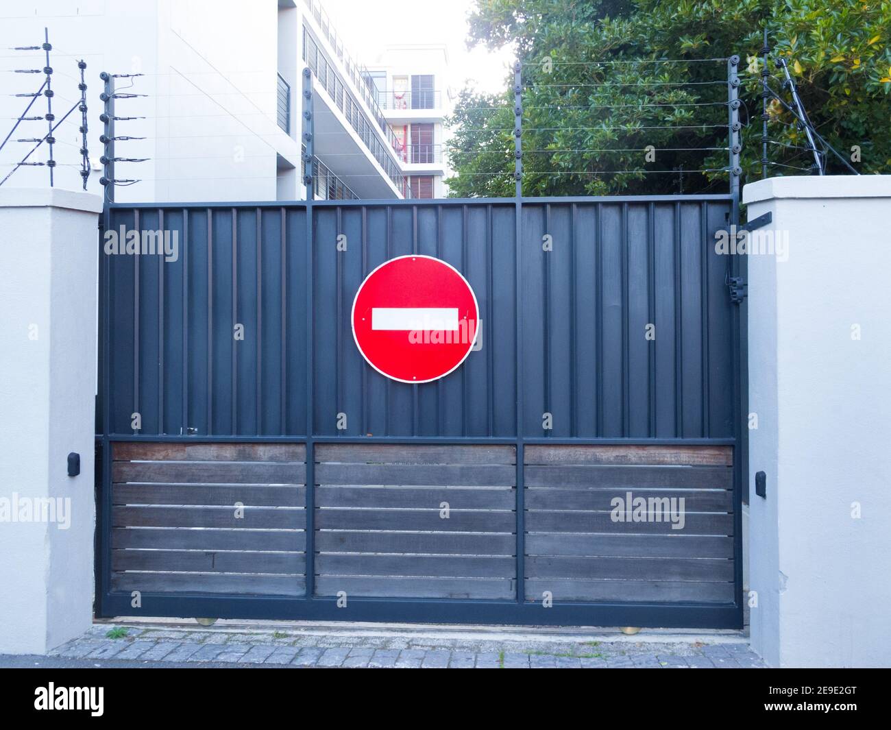 security driveway metal gate with electric fence or wires on top and a no entry sign on the exterior concept safety and security in South Africa Stock Photo