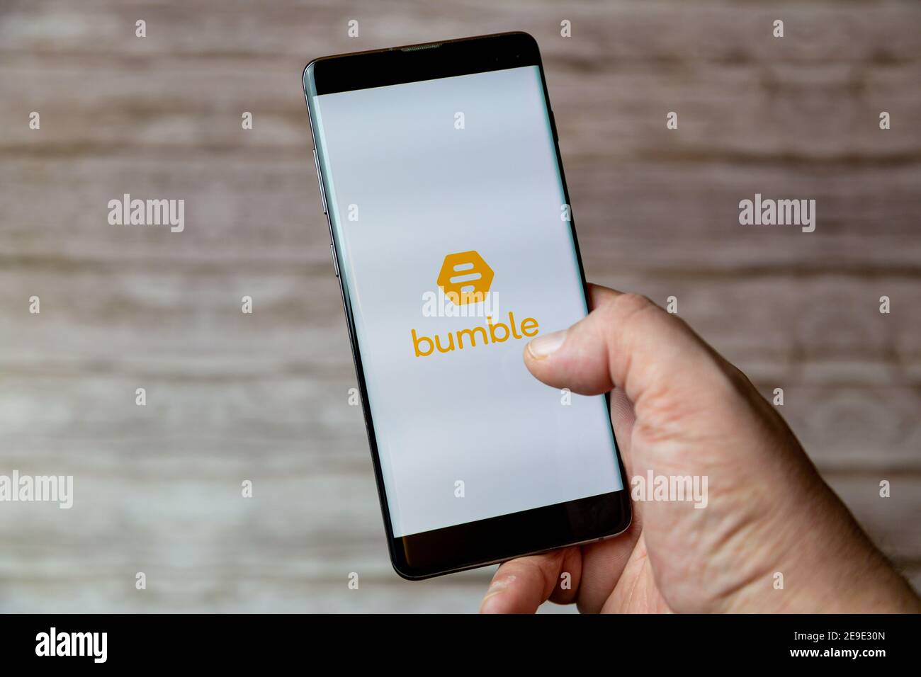 A hand holding a Mobile phone or cell phone with the Bumble online dating app on screen Stock Photo