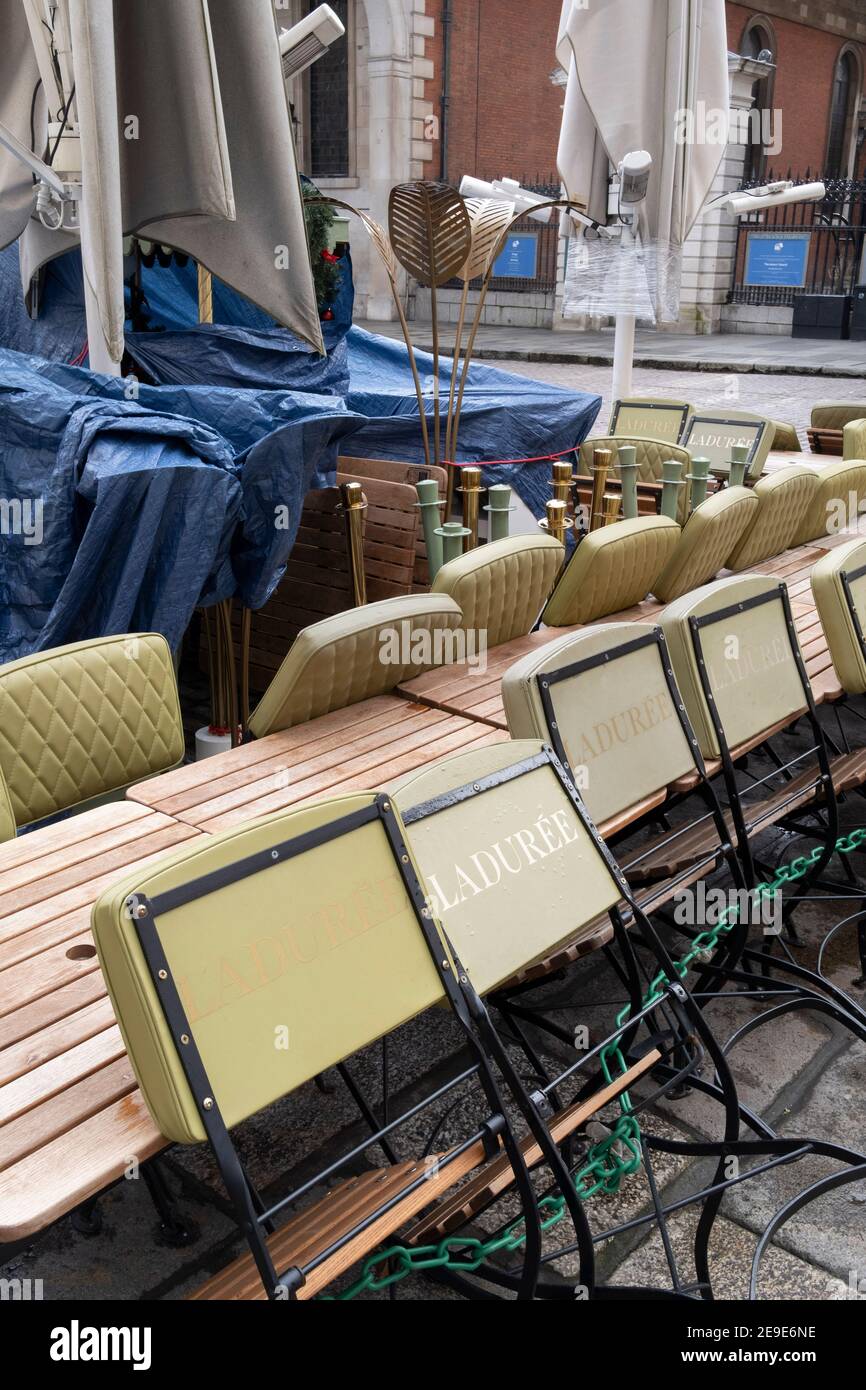 According to the government's Covid social distance restrictions, tables and chairs from a closed restaurant business 'Laduree' are stacked and tied together in the Covent Garden Piazza during the third lockdown of the Coronavirus pandemic, on 3rd February 2021, in London, England. Stock Photo