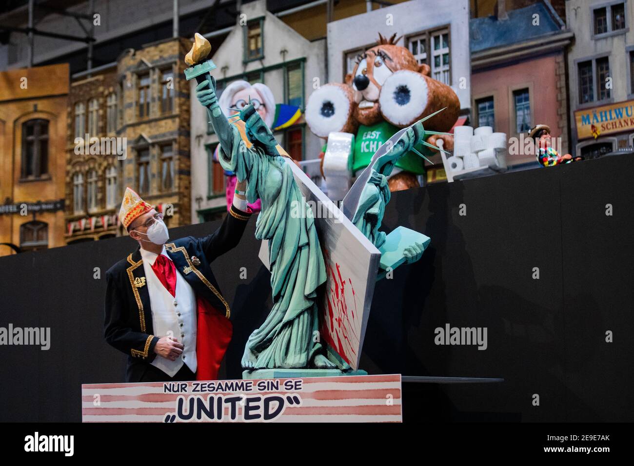 04 February 2021, North Rhine-Westphalia, Cologne: Michael Kramp of the  Festkomitee Kölner Karneval (Cologne Carnival Festival Committee), wearing  a jester's cap and FFP2 mask, stands in front of a float at the