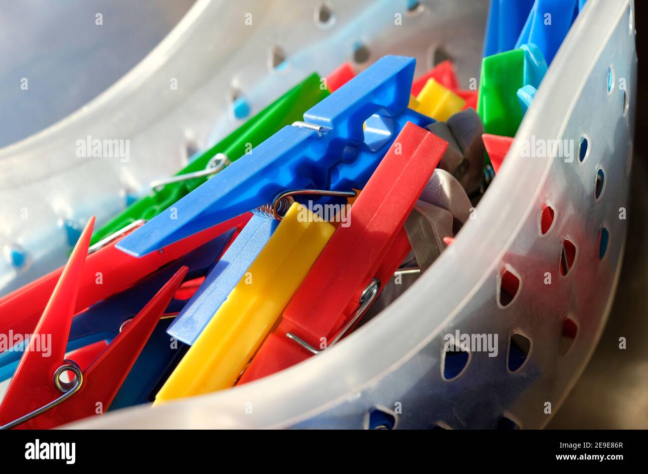 colourful plastic clothes pegs in container Stock Photo