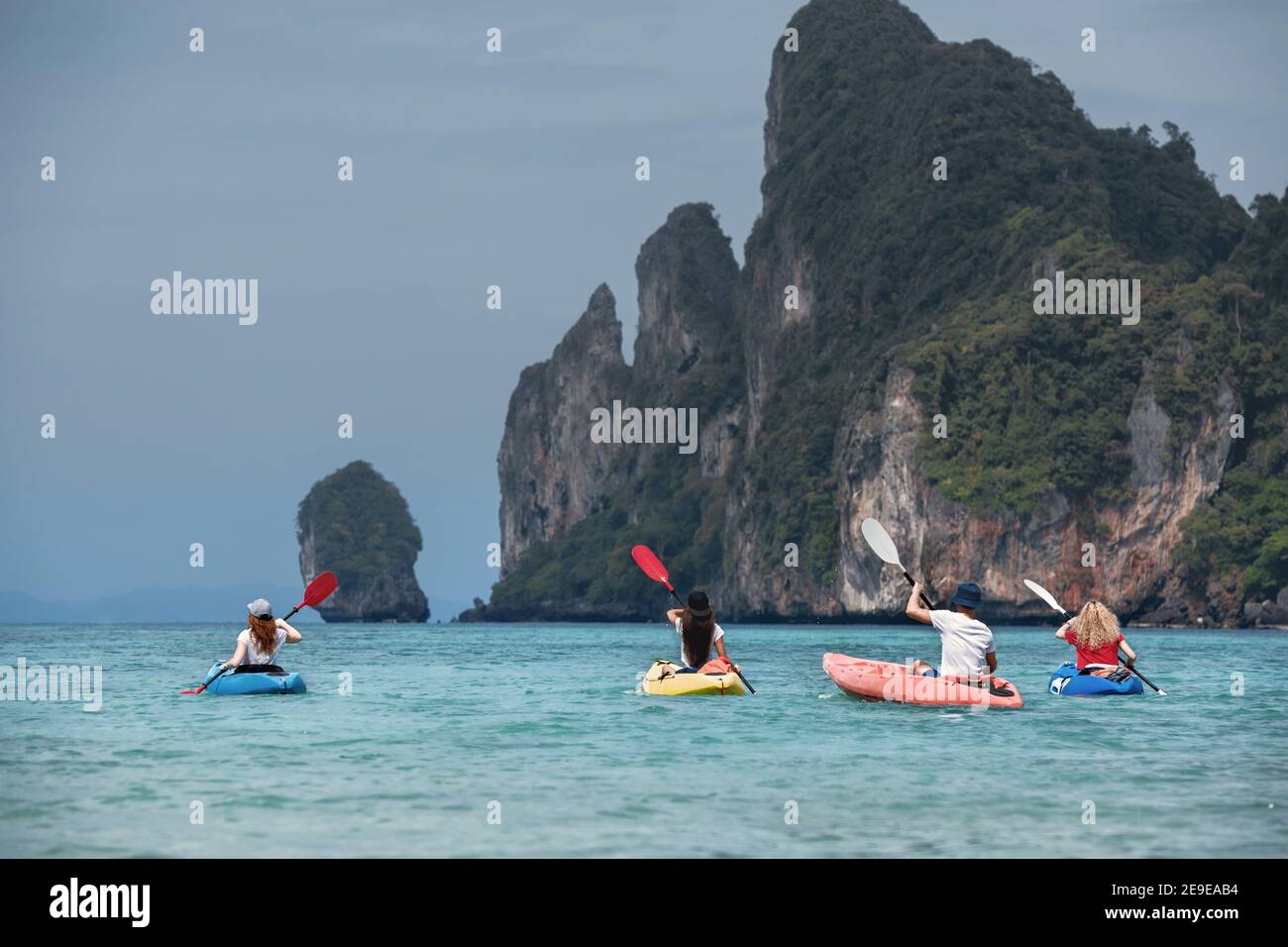 Four friends are walking by sea kayaks or canoes. Phi-Phi Don island, Krabi, Thailand Stock Photo