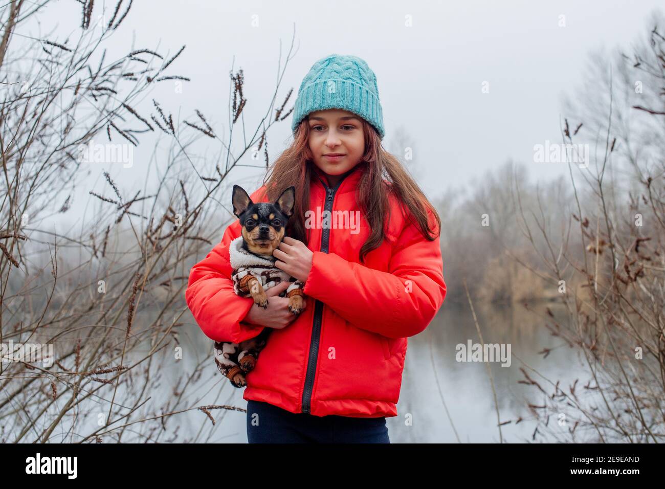 Girl 10 years old. Teenager girl in orange jacket, blue hat. Girl and