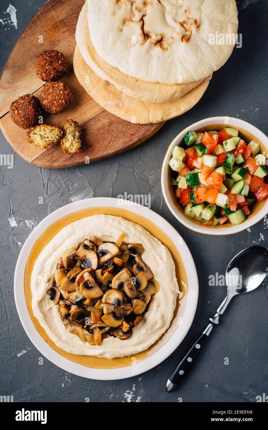 Hummus with fried mushrooms, cucumber and tomato salad, falafel and