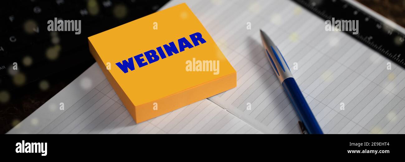 WEBINAR. The text is written on a yellow sticker next to the pen and diary. Education, Internet technology, Webinar, Online courses concept. Stock Photo