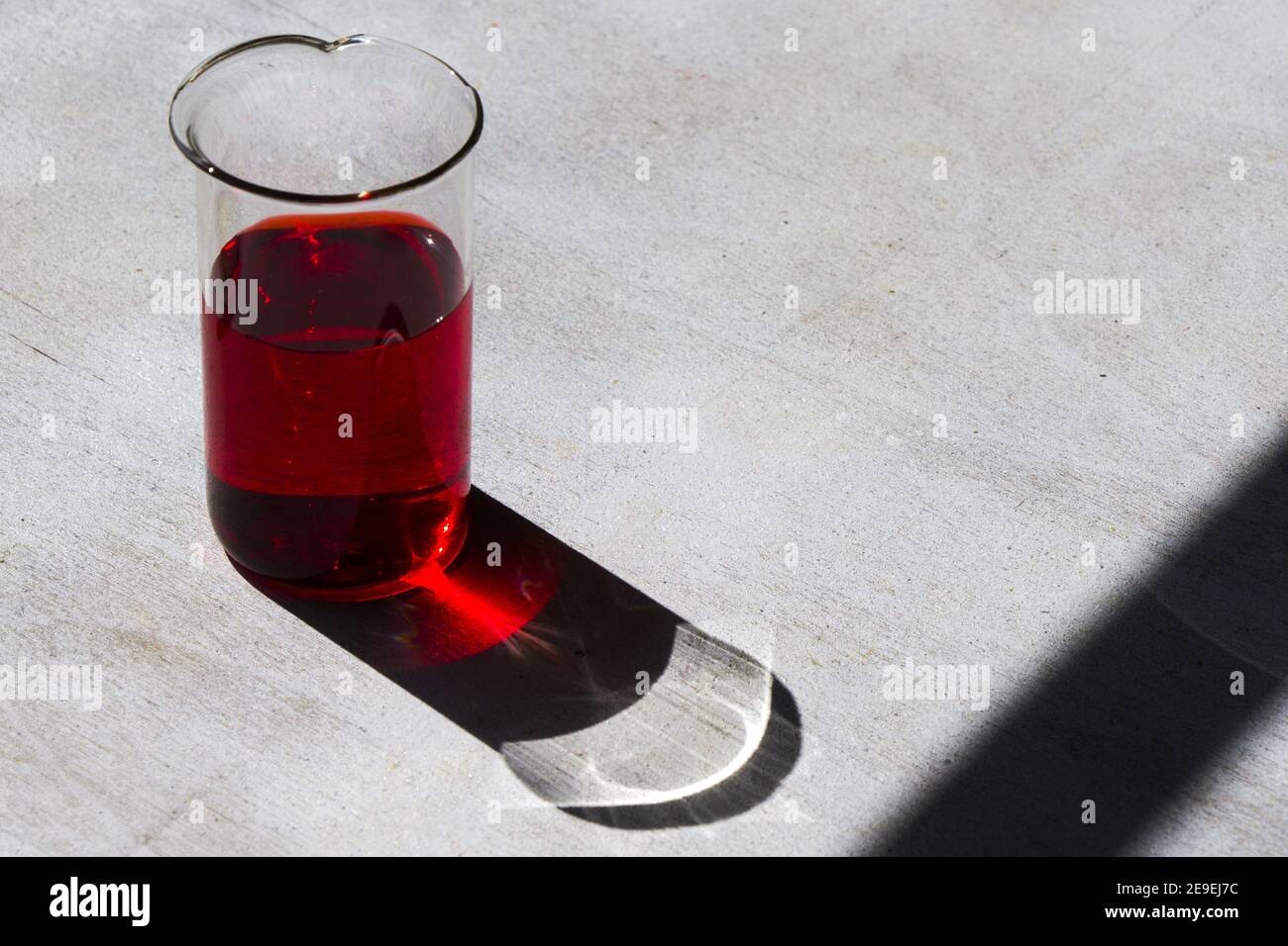 Closeup of laboratory glassware with red reagent under the sunlight ...