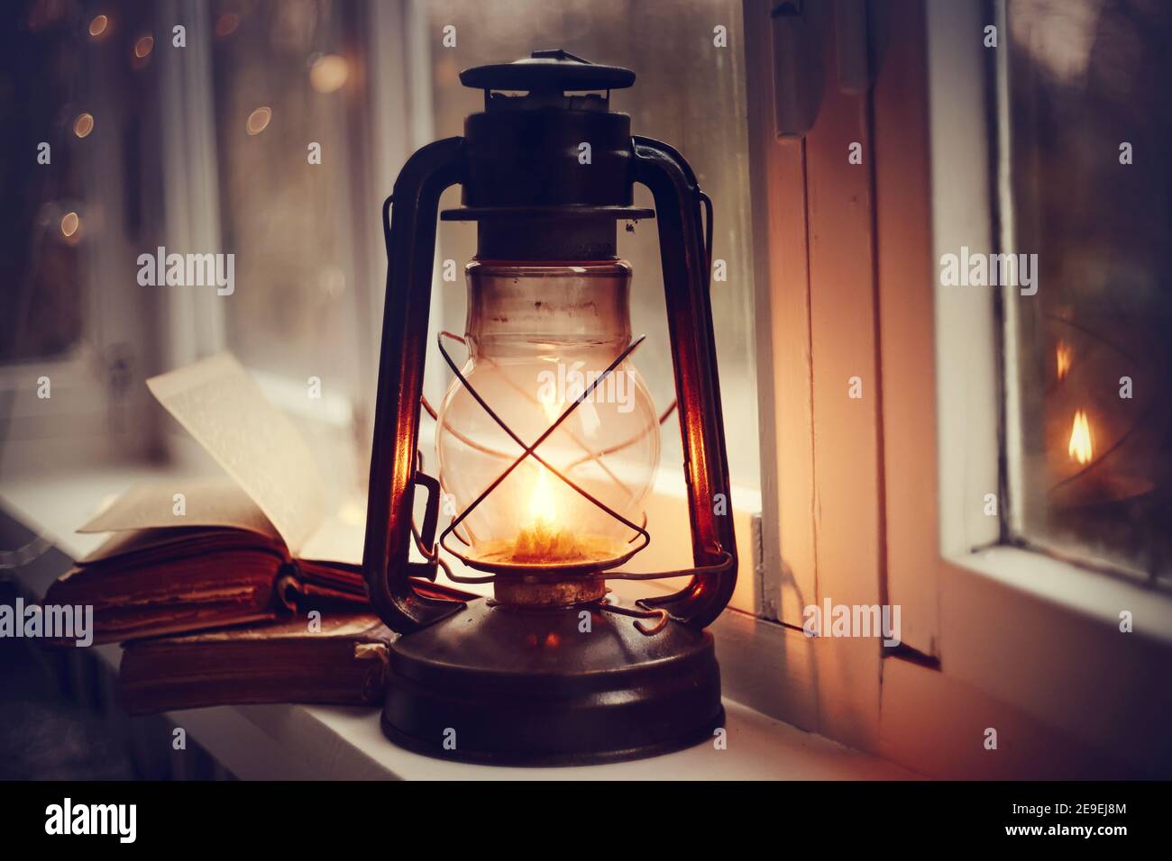 Kerosene lamp and old books on the windowsill. Stock Photo