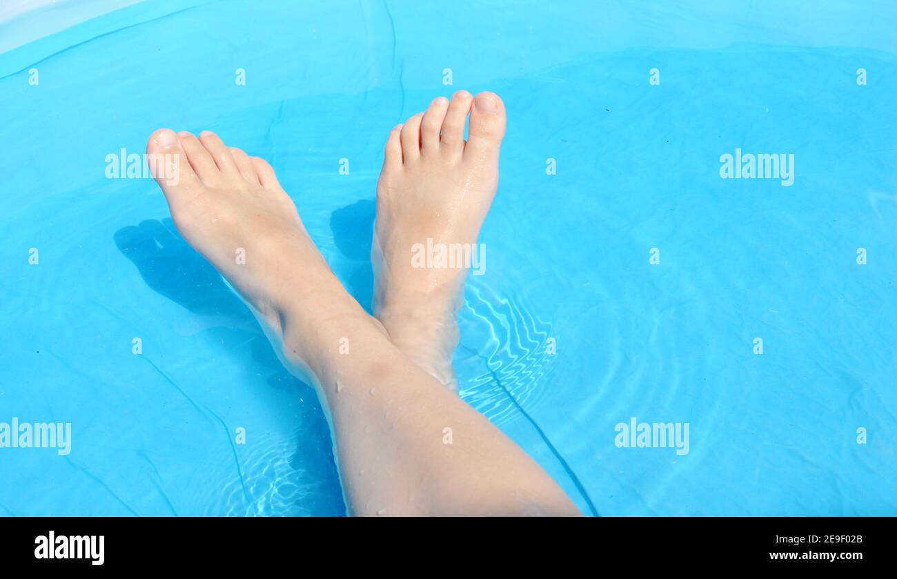 Front view of a white Caucasian girl crossed legs in a blue pool Stock Photo
