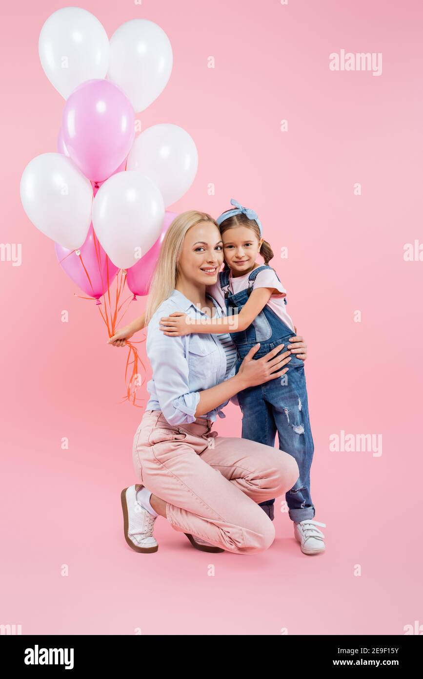 Hugging Balloons happy kid holding balloons and hugging cheerful mother on pink Stock ...