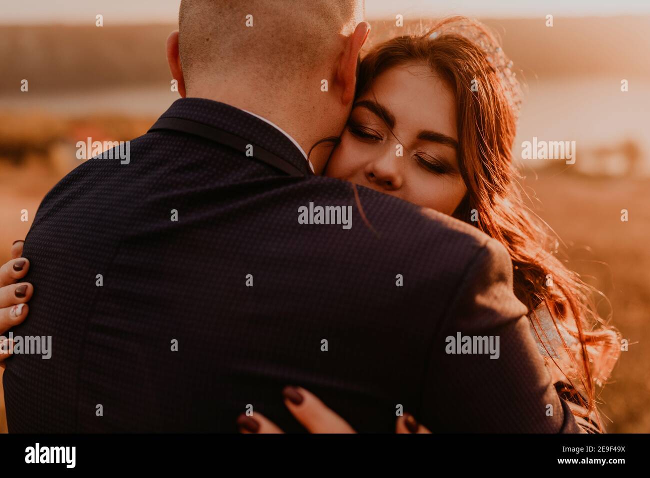 A loving couple wedding newlyweds in white dress and suit walk hug kissing whirl on tall grass in summer field on mountain above the river.style bride Stock Photo